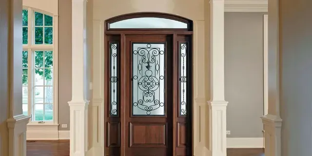 Front entry with a dark wood door, frosted glass panel, and cream columns in a bright foyer