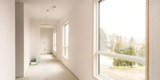 Bright empty hallway with white walls, large windows, and daylight streaming in