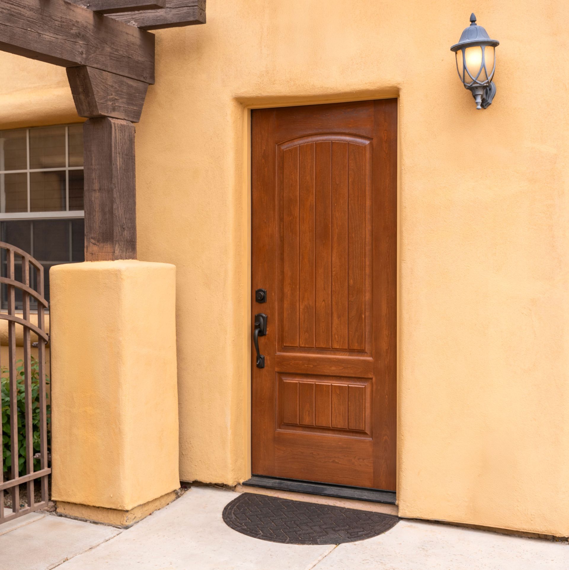Wooden front door with a wall lantern on a stucco house entrance