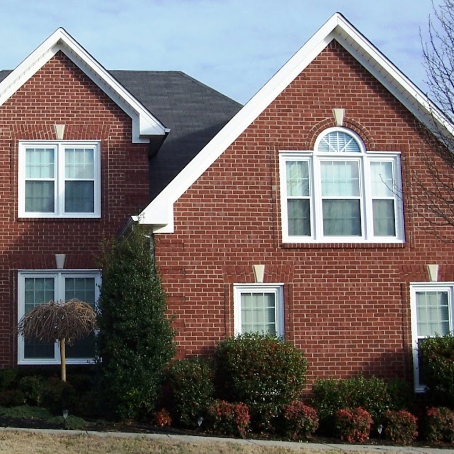 Newly installed white replacement windows on a brick home