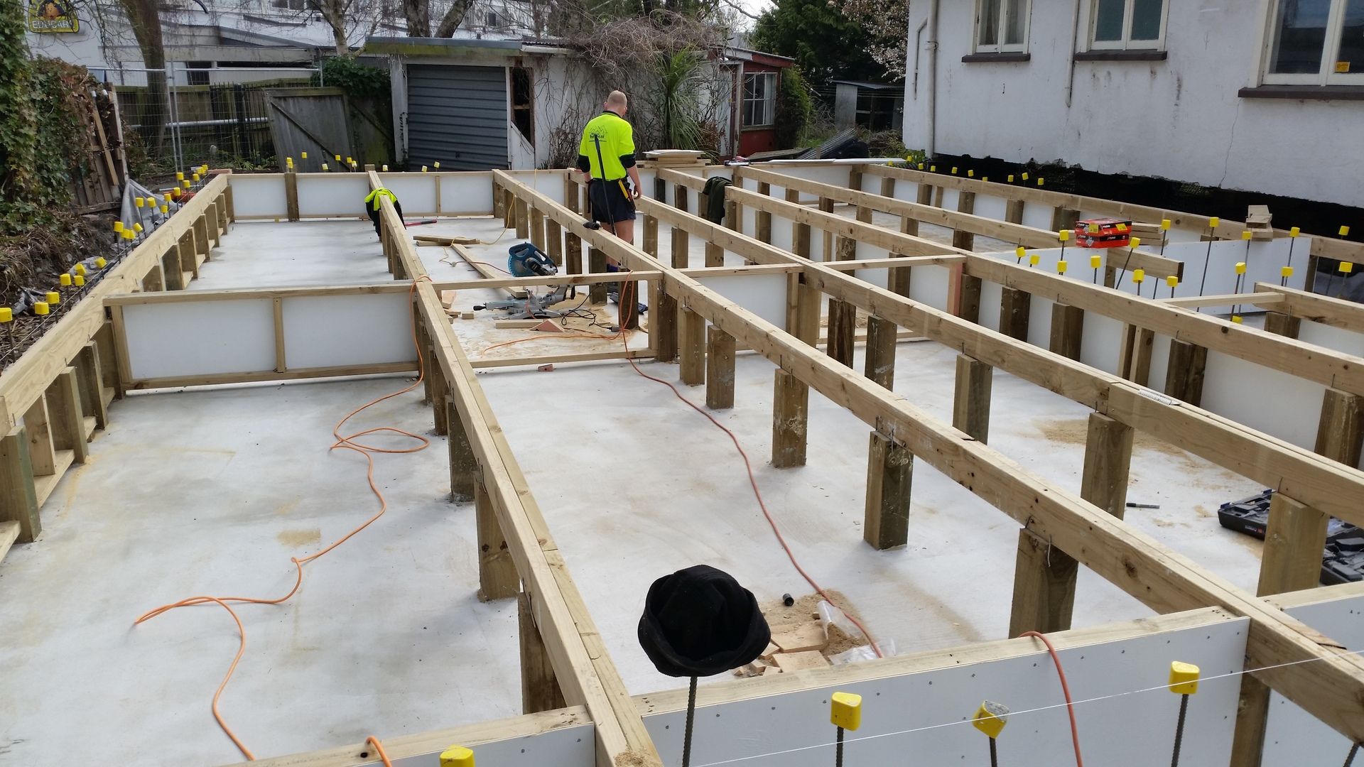 A man is standing on a wooden deck under construction.