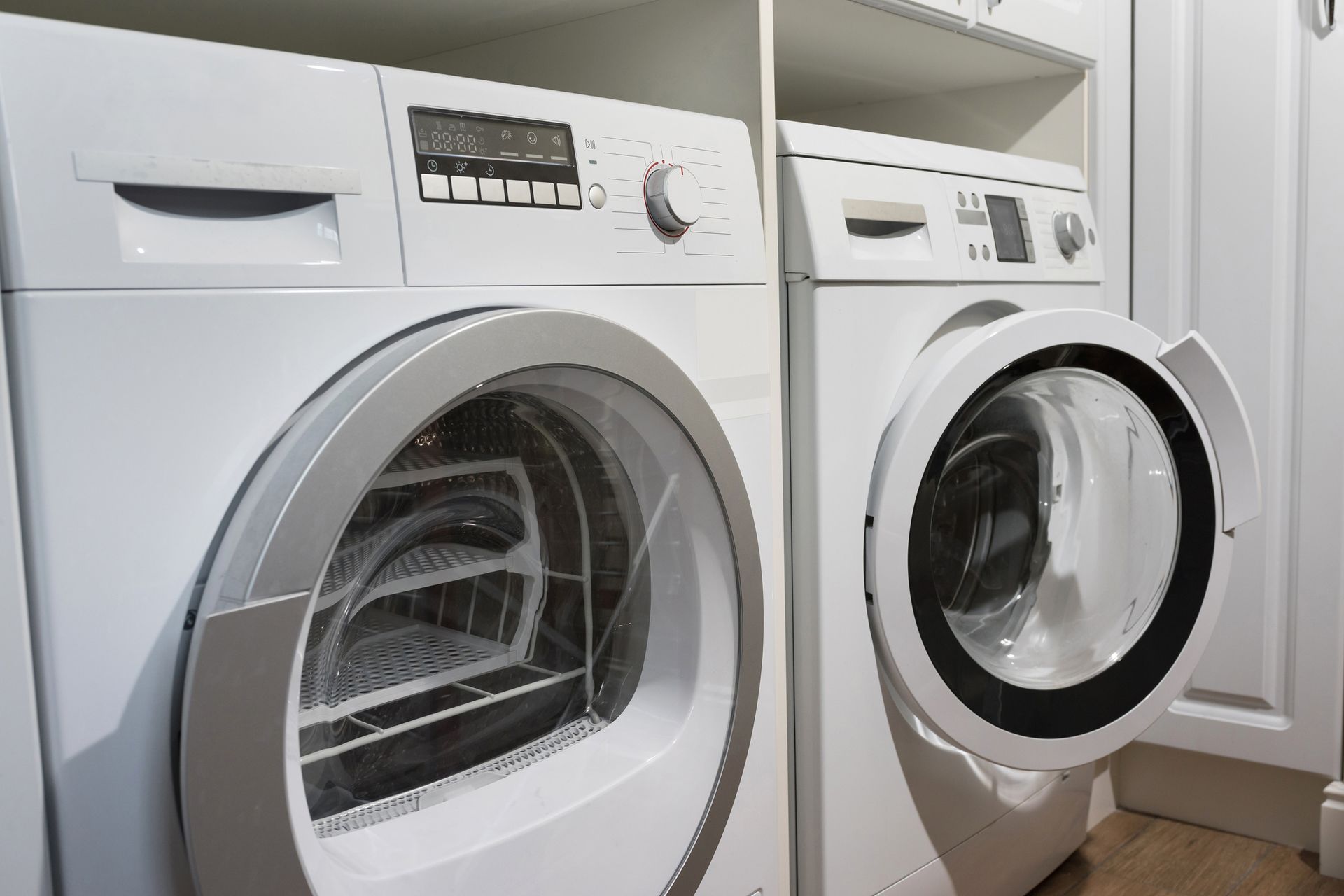 White front-loading washing machine and dryer in a laundry room.