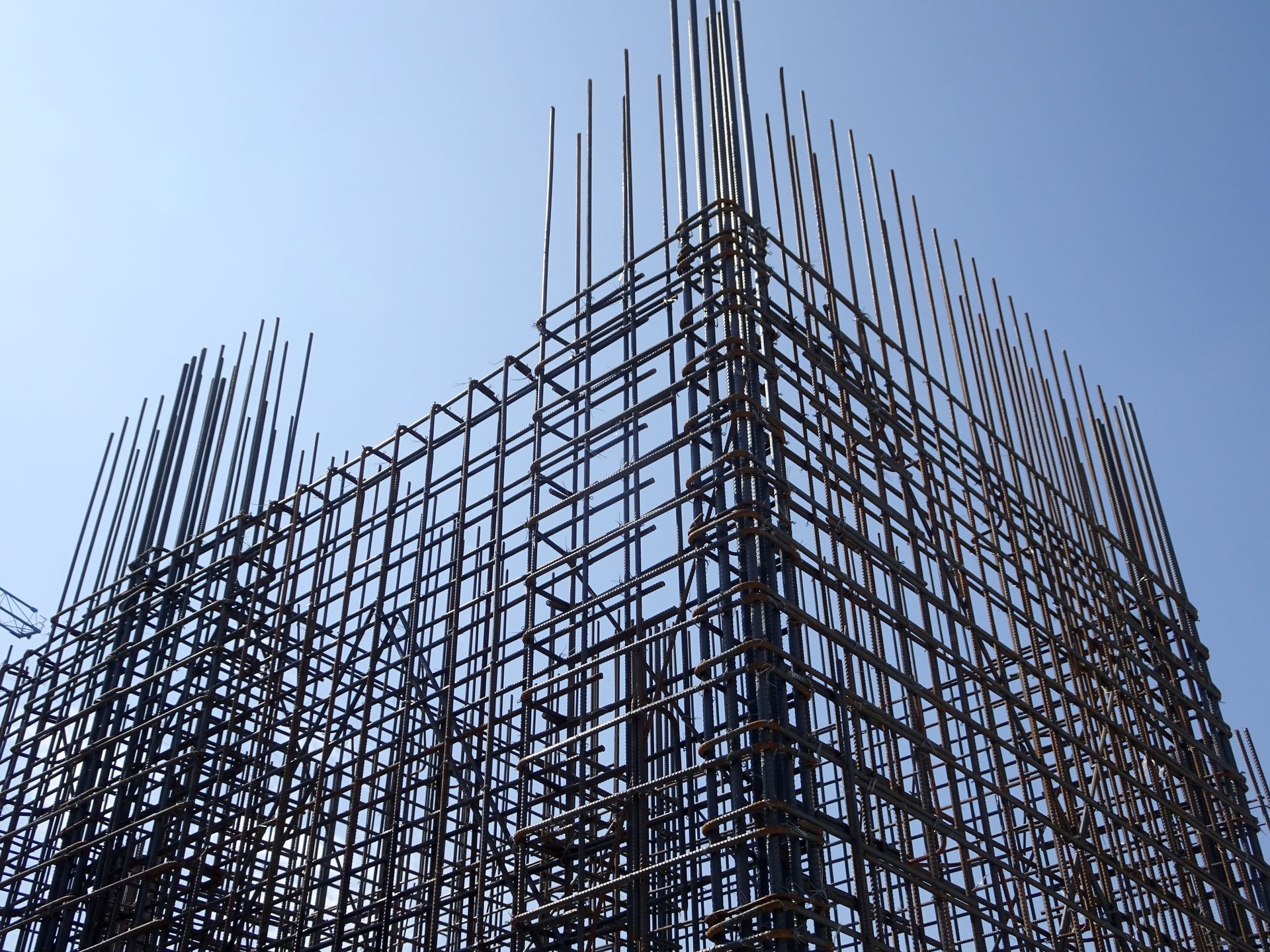 Steel rebar framework of a building under construction against a blue sky