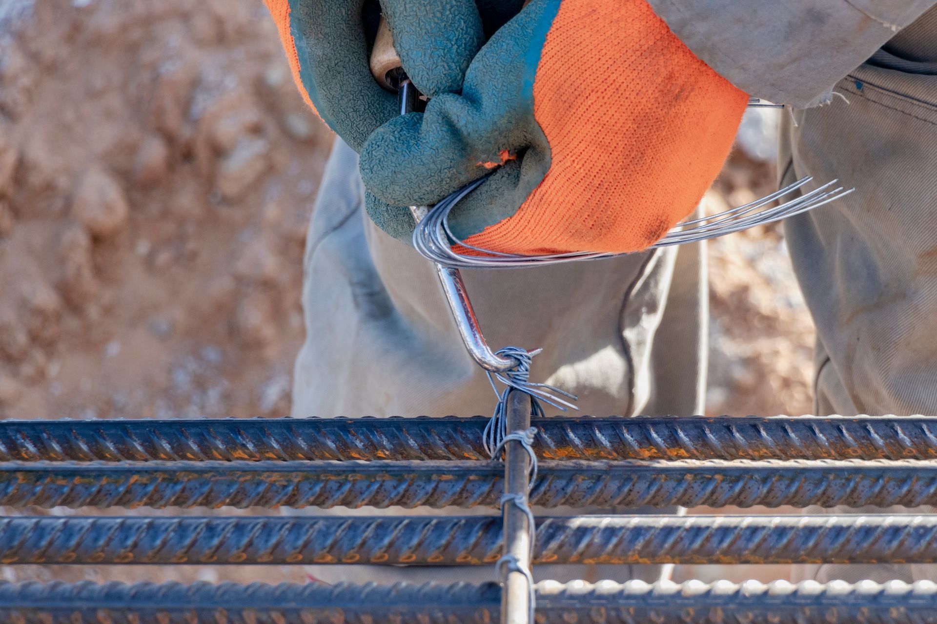 A worker is using tie wire to reinforce bars in a construction site.