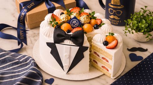 Decorated cake with strawberries and chocolate, topped with a black bow and fruit, on a festive table