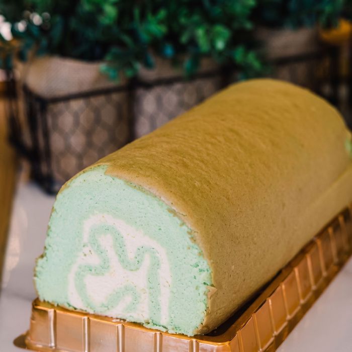 Green Swiss roll cake slice with pale filling on a gold tray