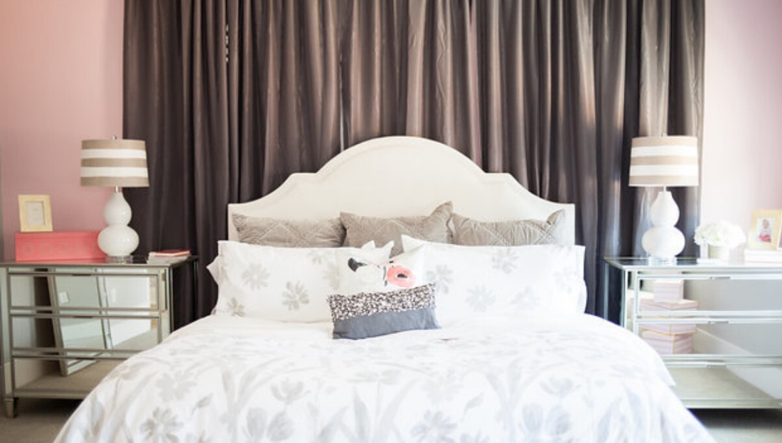 A bedroom with a bed , nightstands , lamps and curtains.