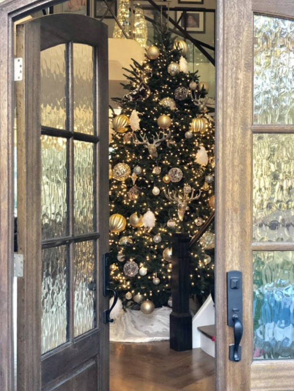 A christmas tree is behind a door that is open
