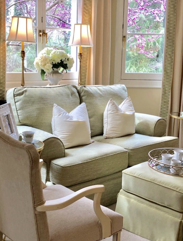 A living room with a green couch and white pillows