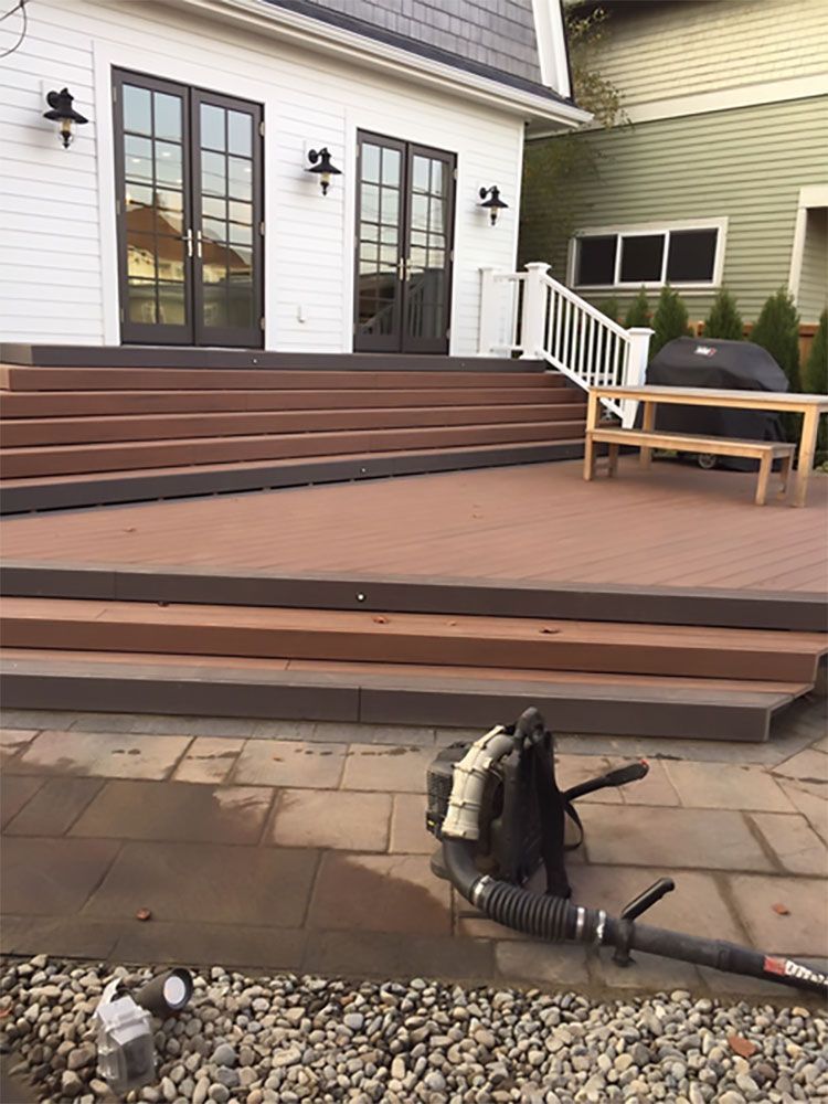 A backpack blower is sitting on a patio next to a house.