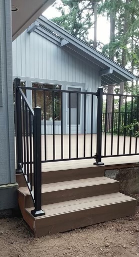A deck with stairs and a metal railing next to a house.