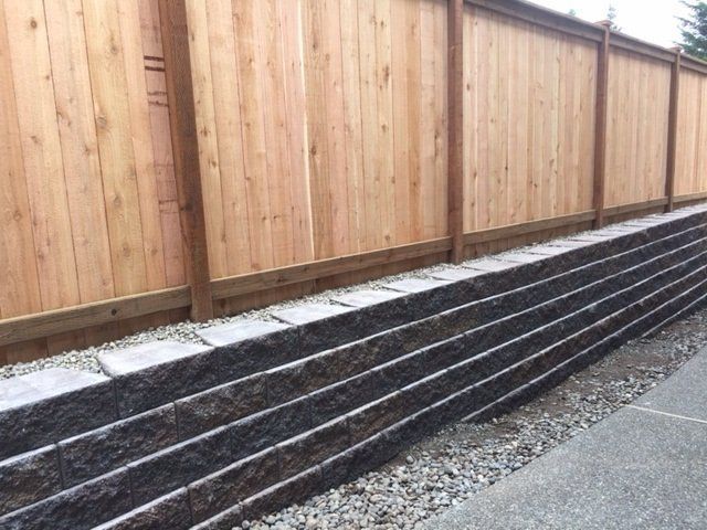 A wooden fence is sitting next to a stone wall.