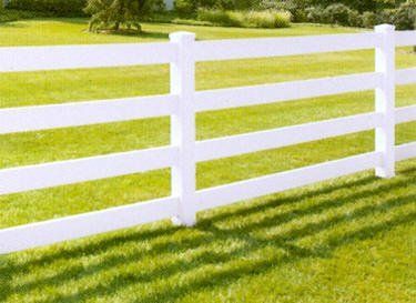 A white fence is sitting in the middle of a lush green field.