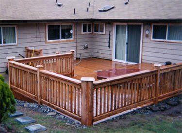 A wooden deck with a fence around it in front of a house.