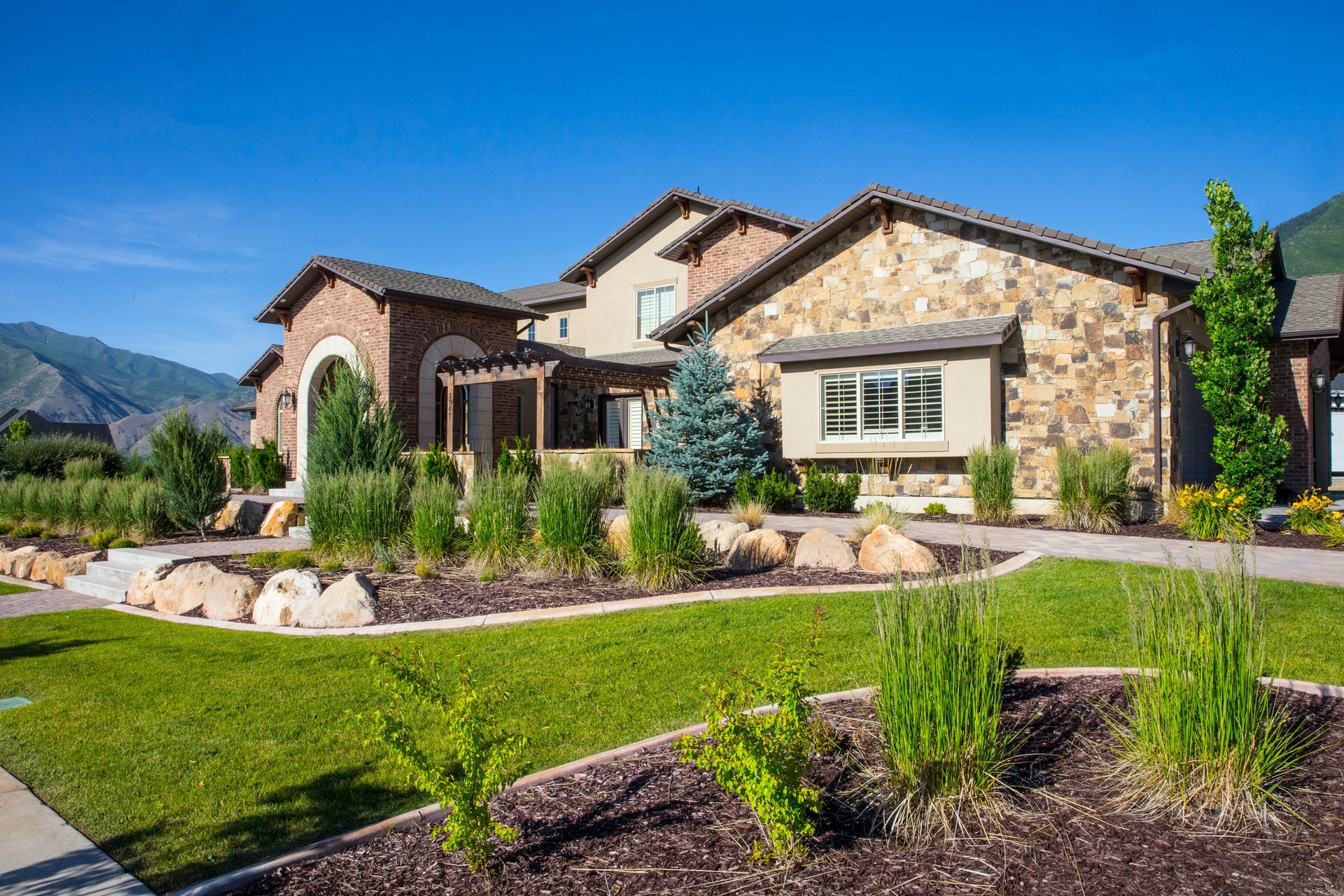 A large stone house with a lush green lawn in front of it.
