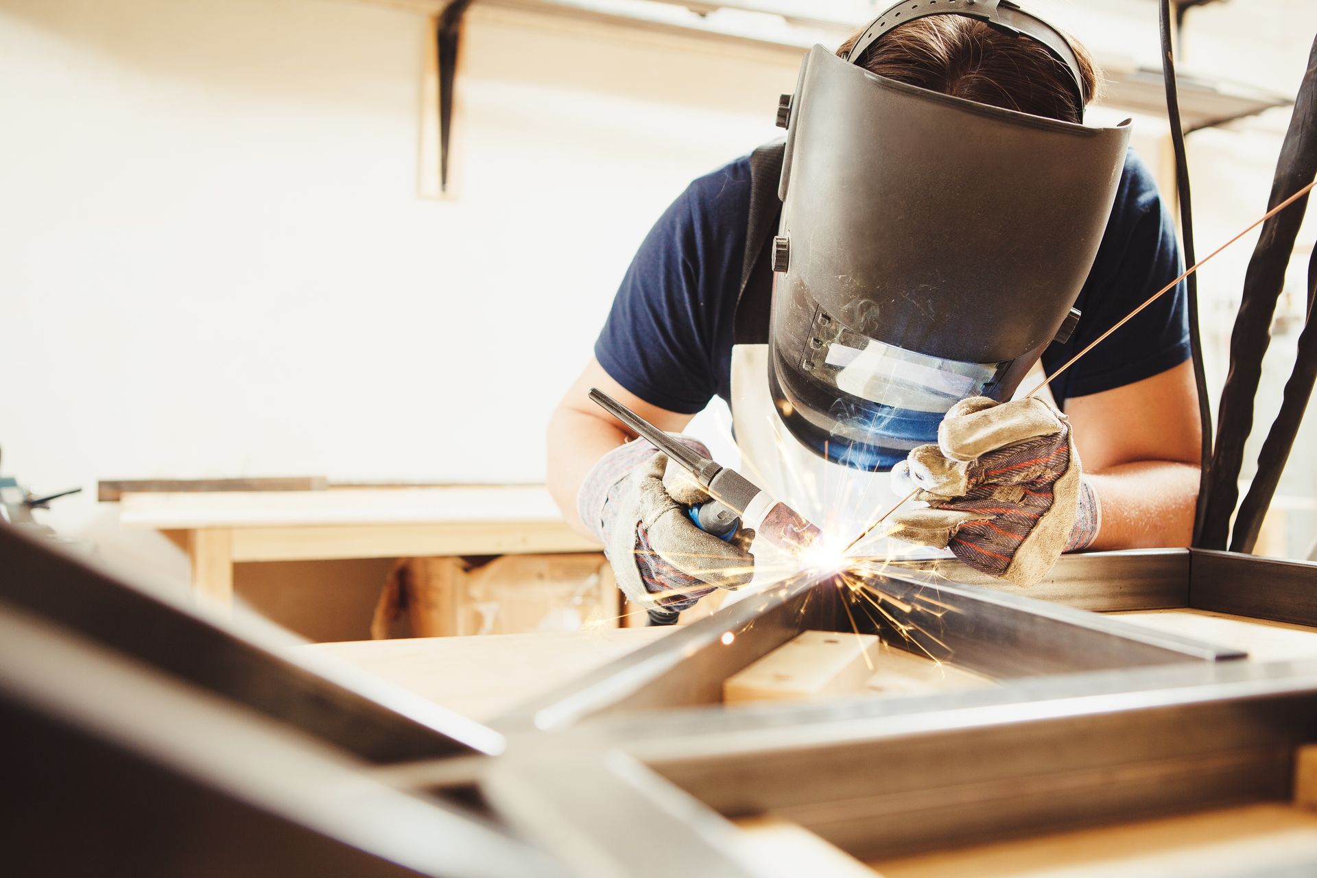 worker wearing a welding helmet carefully joins metal pieces with a bright weld arc. worker wearing a welding helmet carefully joins metal pieces with a bright weld arc.