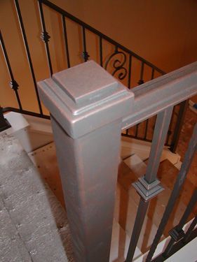 A staircase with a metal railing and a wooden post