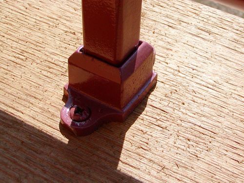 A wooden post with a red base is sitting on a wooden surface
