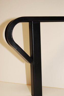 A black metal railing is sitting on a white surface.