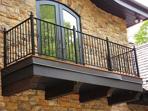 A balcony on the side of a brick building with a wrought iron railing.