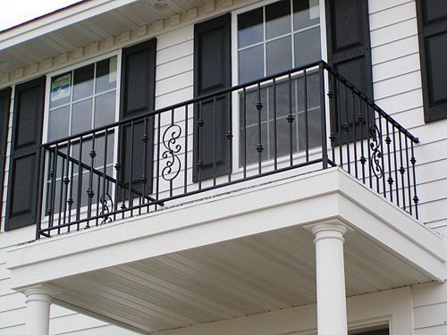 A white house with black shutters and a balcony