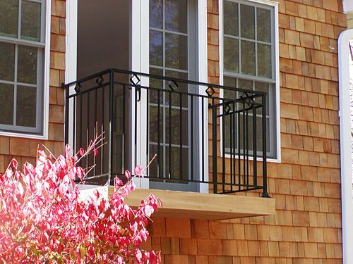 A balcony with a wrought iron railing on the side of a house