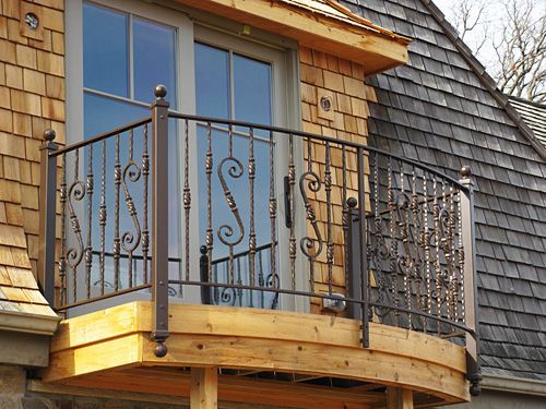 A balcony with a wrought iron railing on the side of a house.