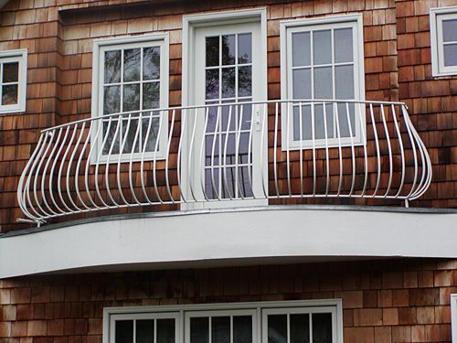 A balcony on the side of a house with a stainless steel railing