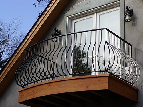 A balcony on the side of a house with a wrought iron railing