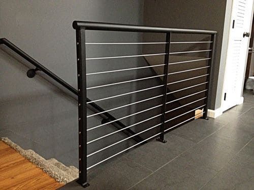 A staircase with a black railing and a wooden handrail