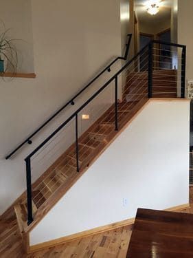 A wooden staircase with a black railing in a living room