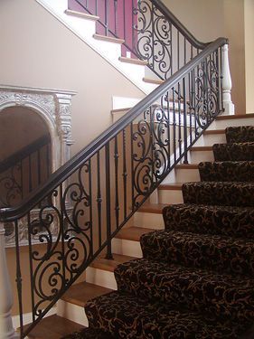 A staircase with a wrought iron railing and a carpeted staircase