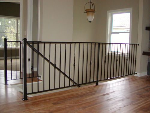 A staircase with a wrought iron railing and a wooden floor
