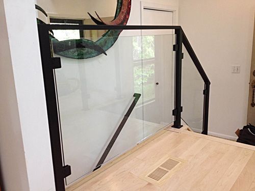 A staircase with a glass railing and a black railing in a house.