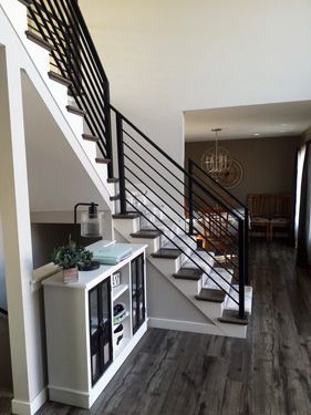 A staircase in a house with a black railing and a white cabinet underneath it.