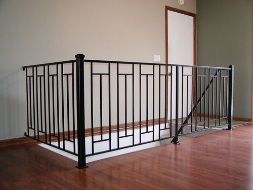 An empty room with a wrought iron railing on the stairs