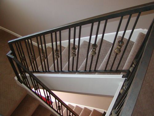A staircase with a metal railing and a carpeted staircase.
