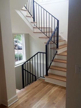 A staircase with a black railing and wooden steps in a house.