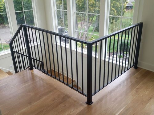 A staircase with a black railing and a large window.