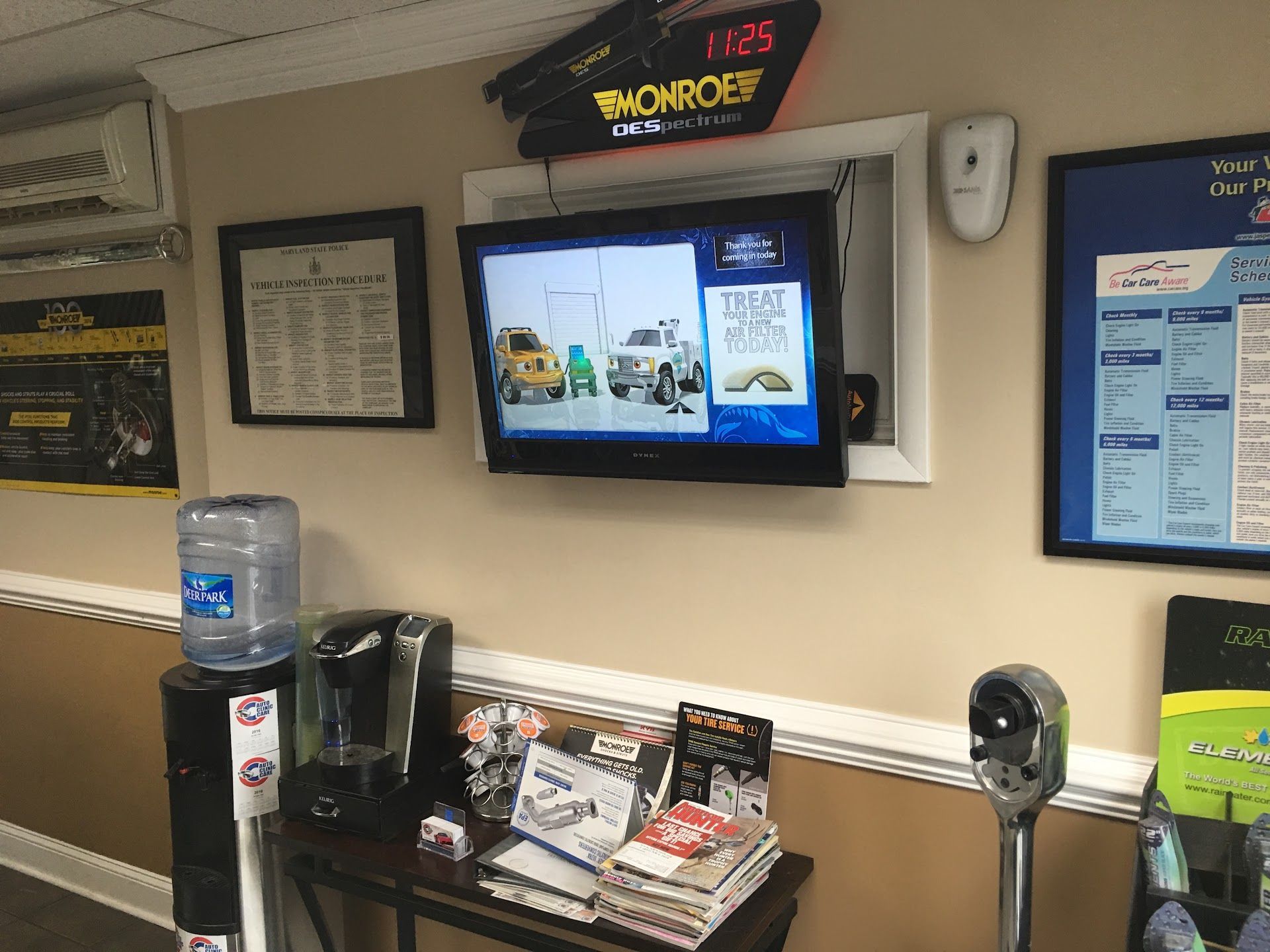 Lobby kiosk with wall-mounted TV, water cooler, and brochures in a waiting area | Auto Clinic Care