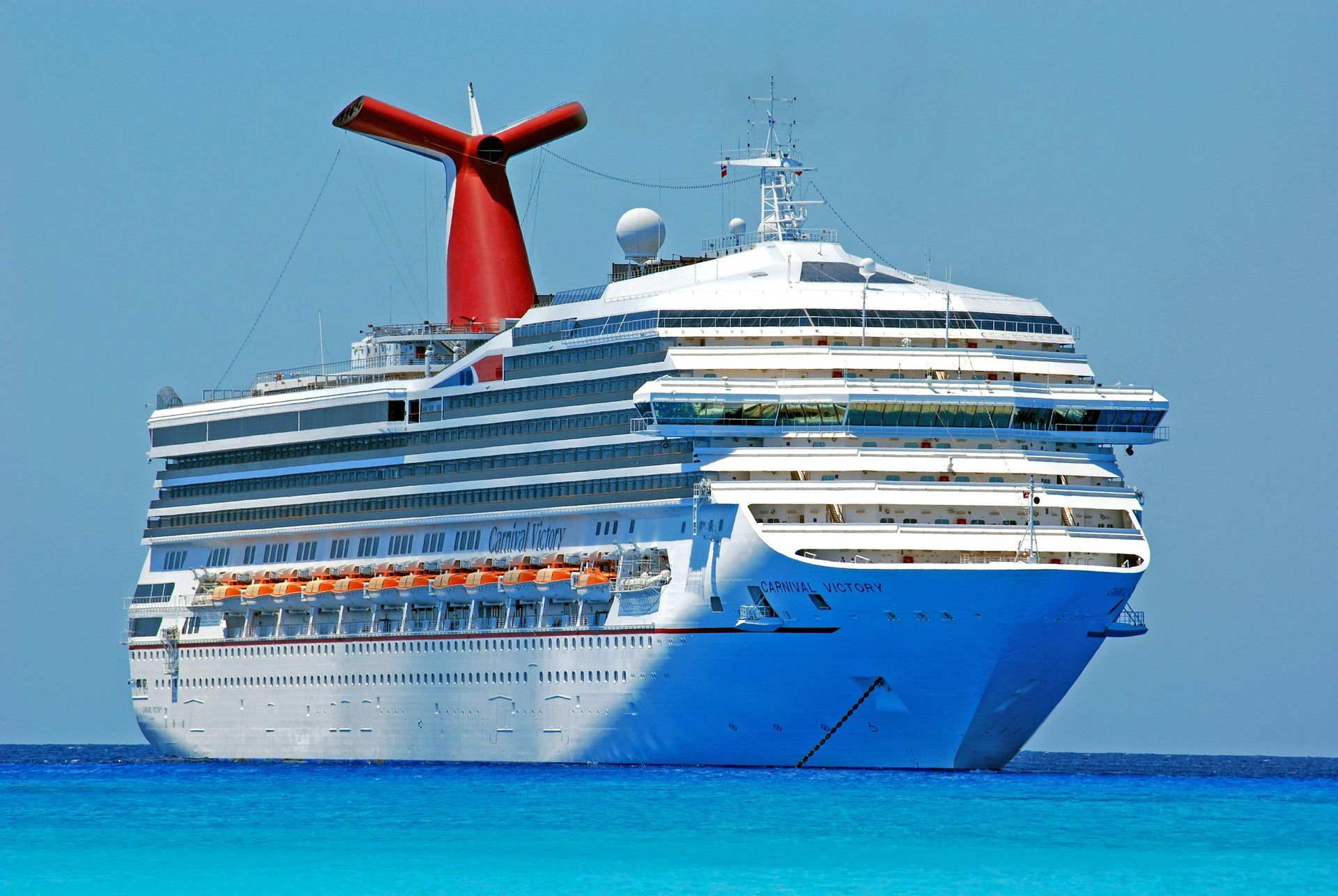 Cruise ship on blue water with red, white, and blue funnel.