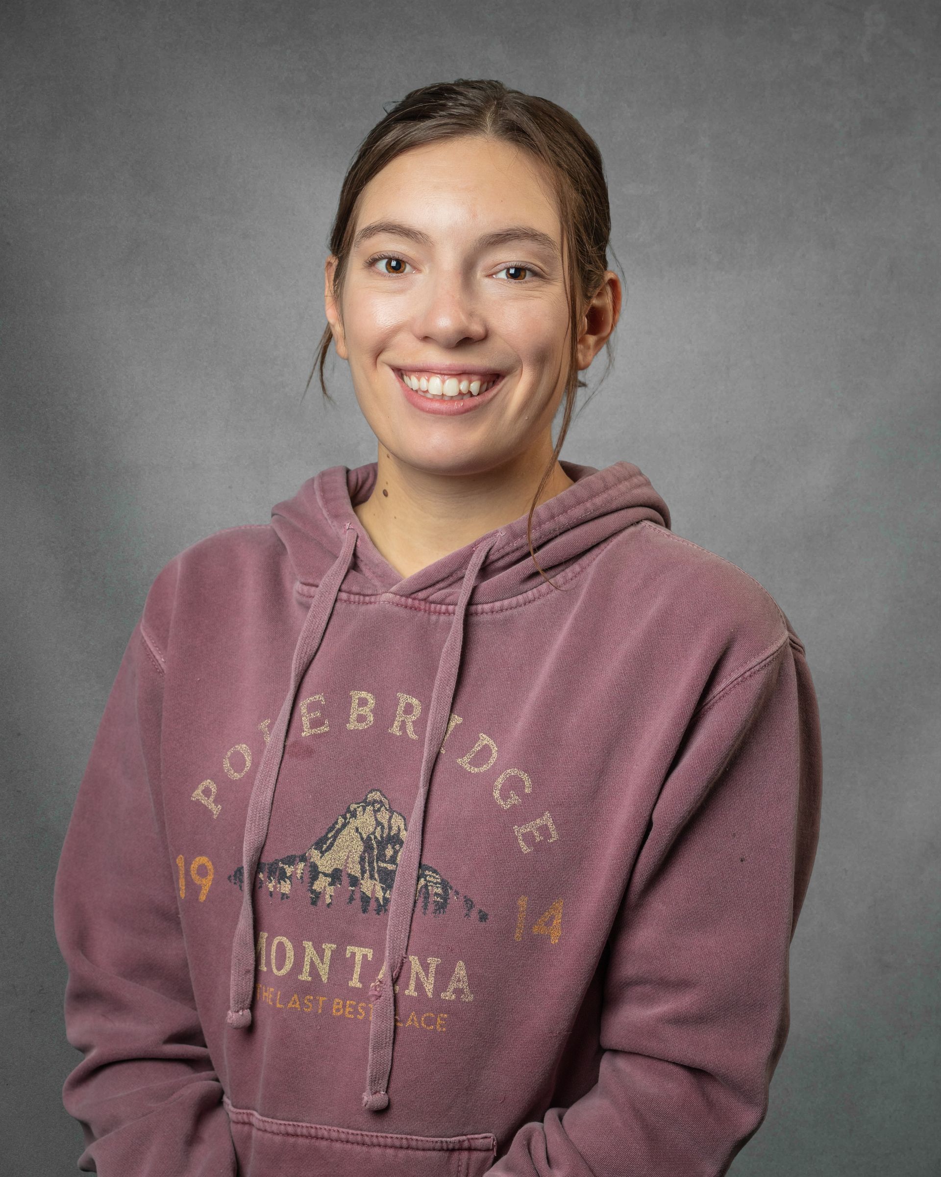 A woman wearing a faded red sweatshirt is smiling.