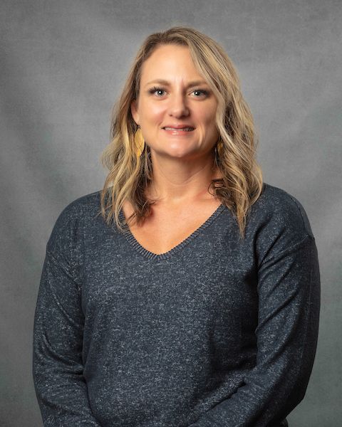 A woman in a dark gray sweater is smiling for the camera.