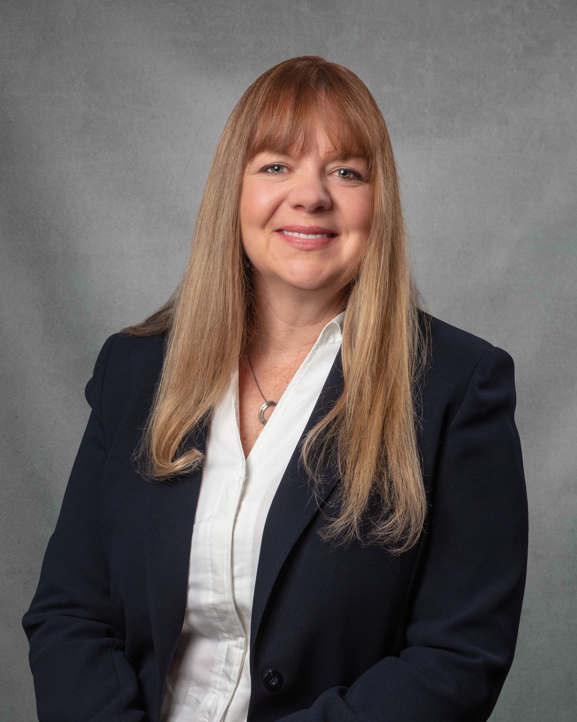 A woman wearing a black blazer is smiling for the camera.