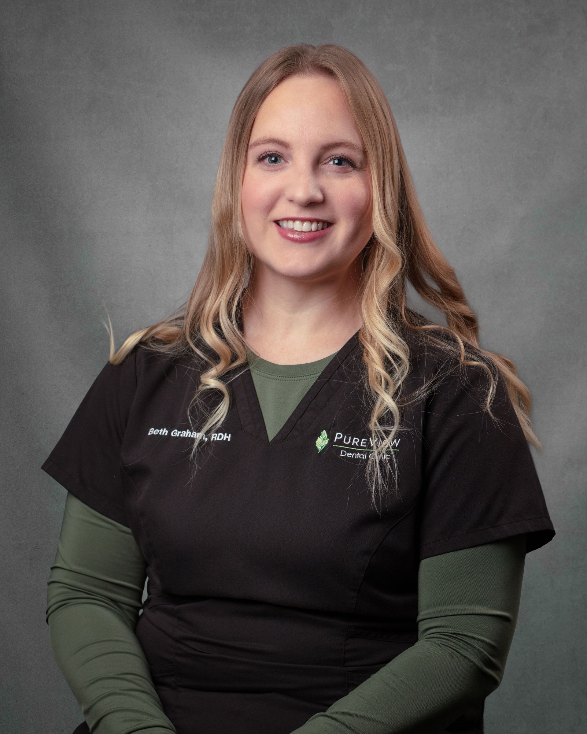 A woman in black scrubs is smiling