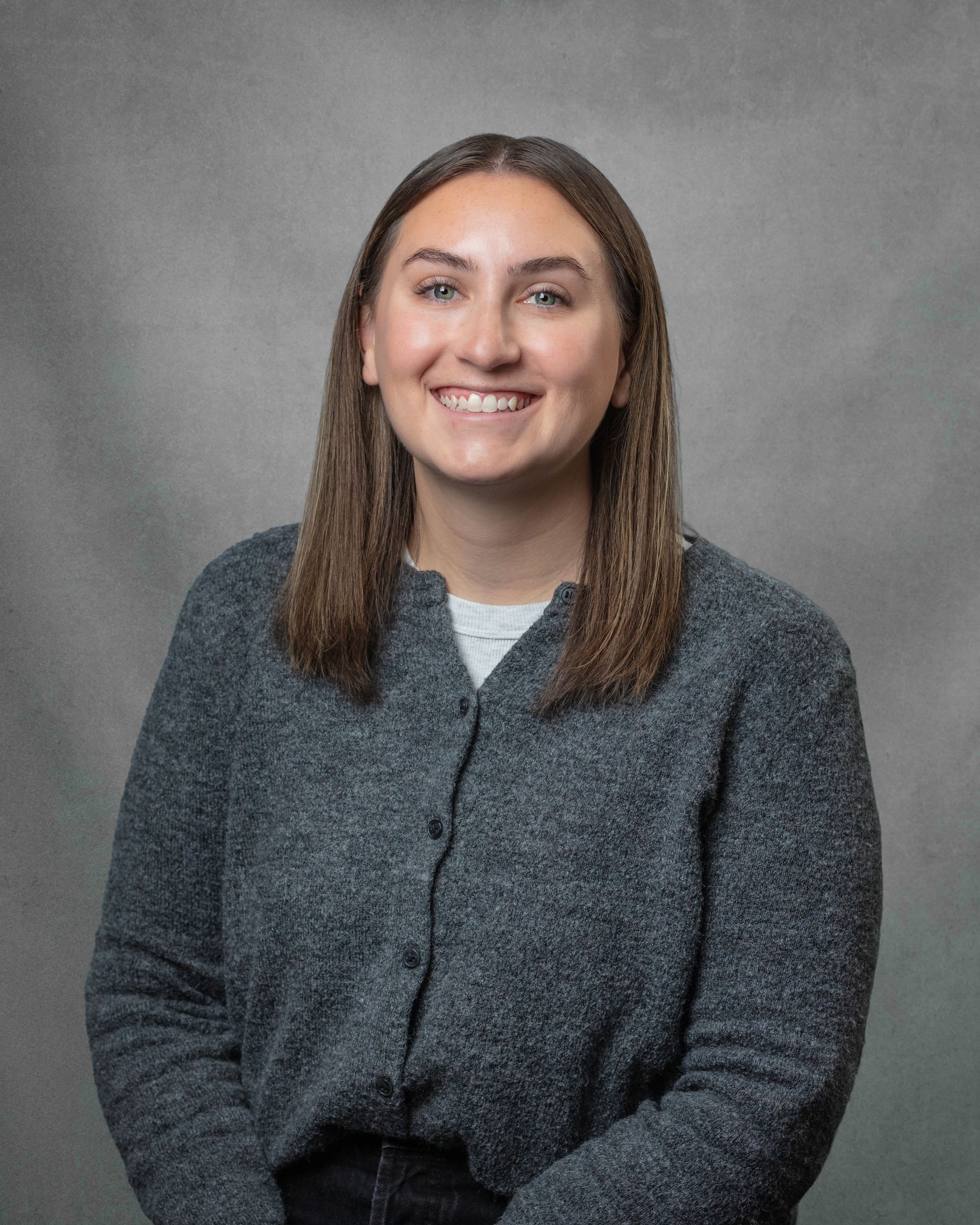 A woman in a gray sweater is smiling 