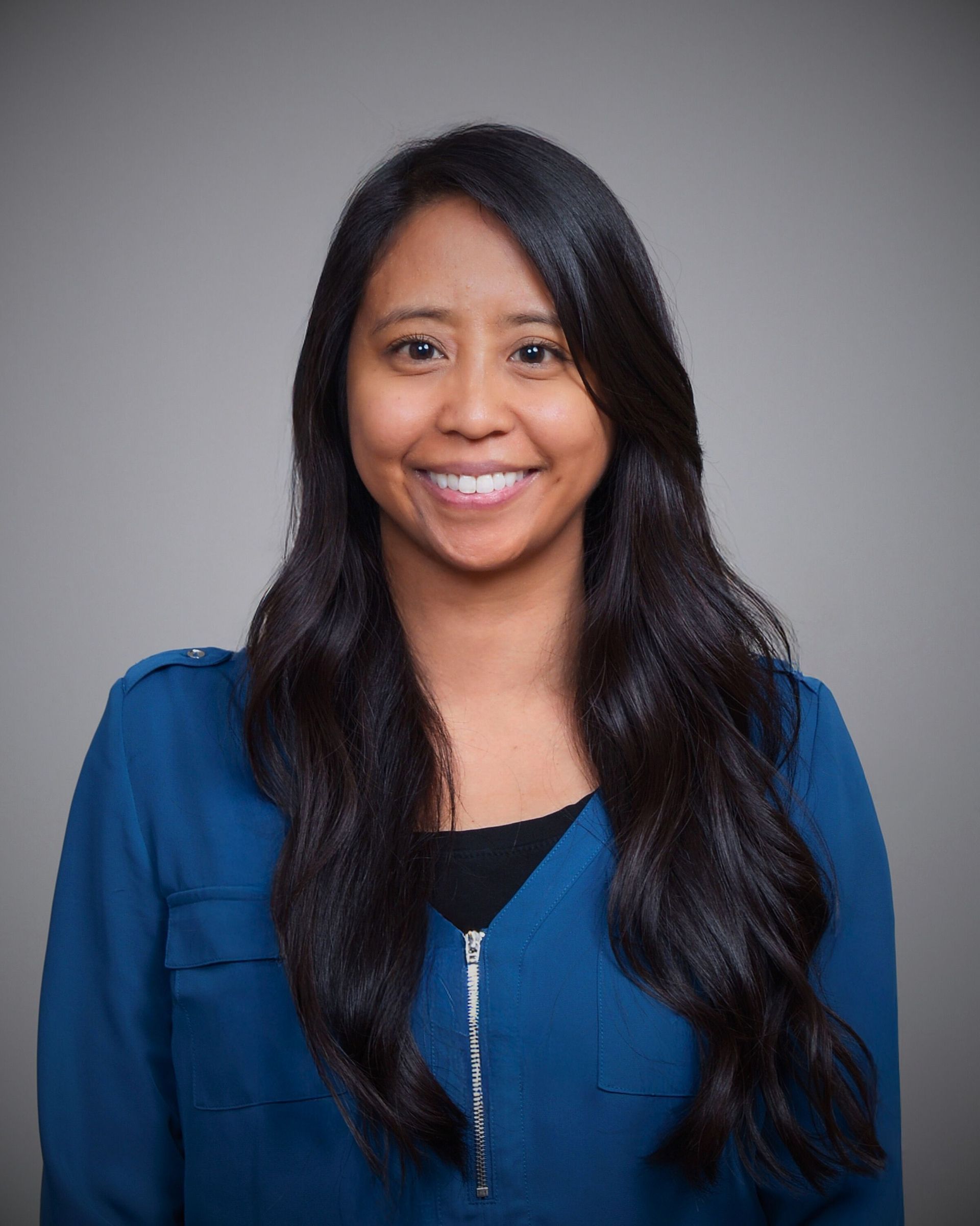 A woman in a blue shirt is smiling for the camera.