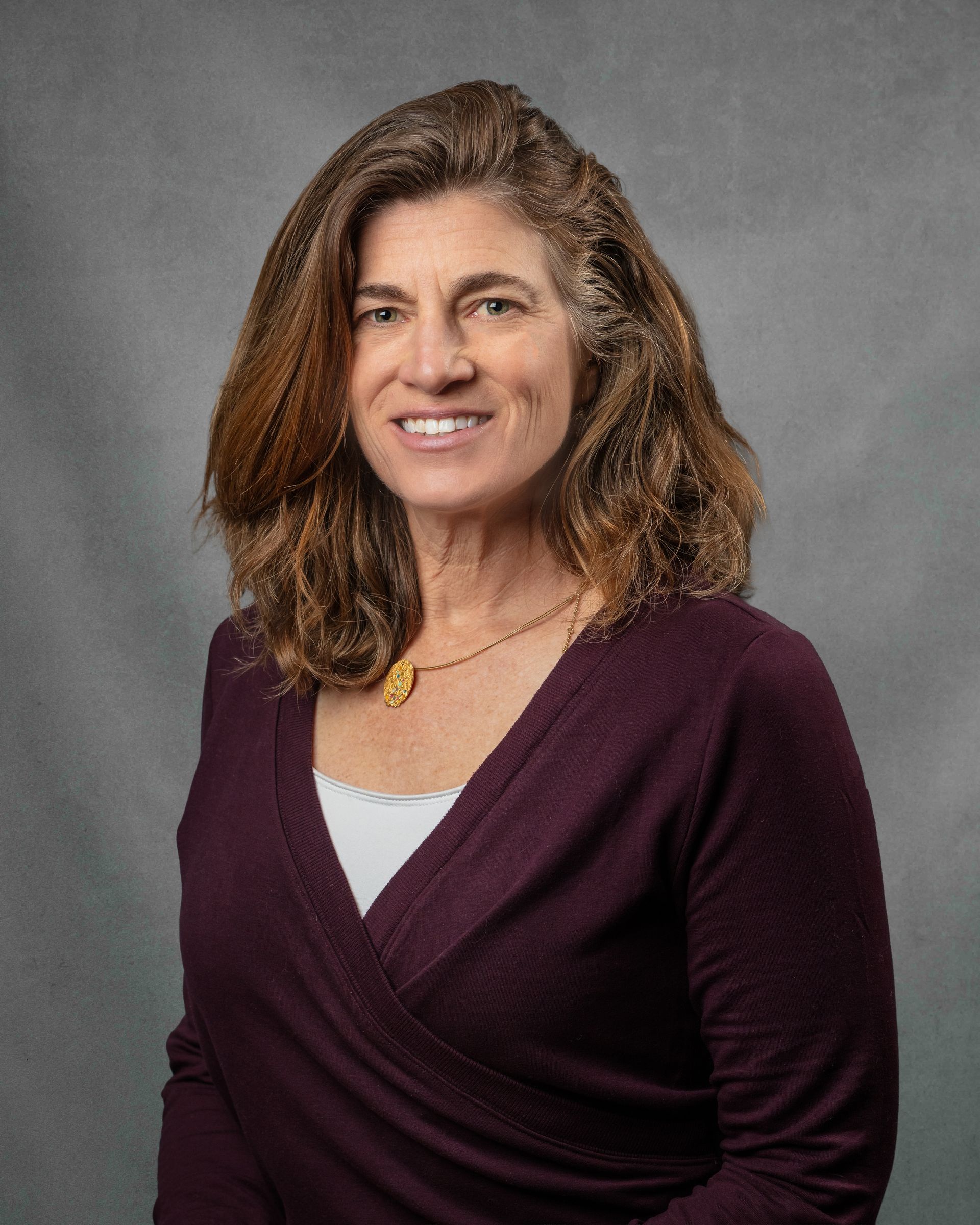 A woman in a maroon shirt is smiling.