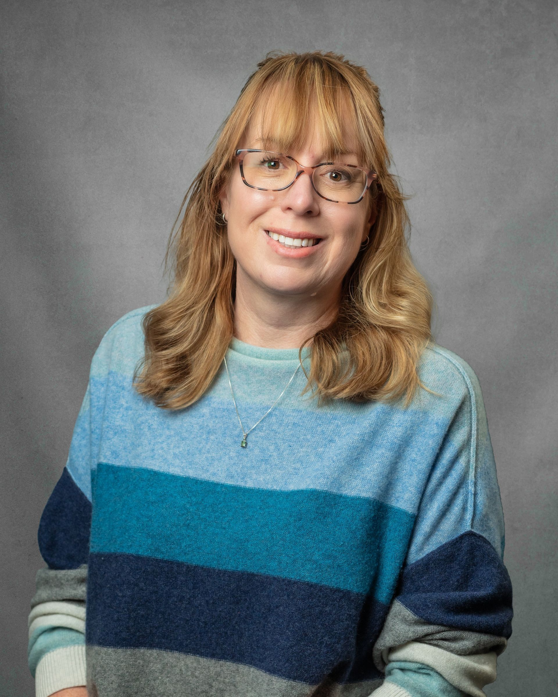 A woman wearing a scarf is smiling for the camera.
