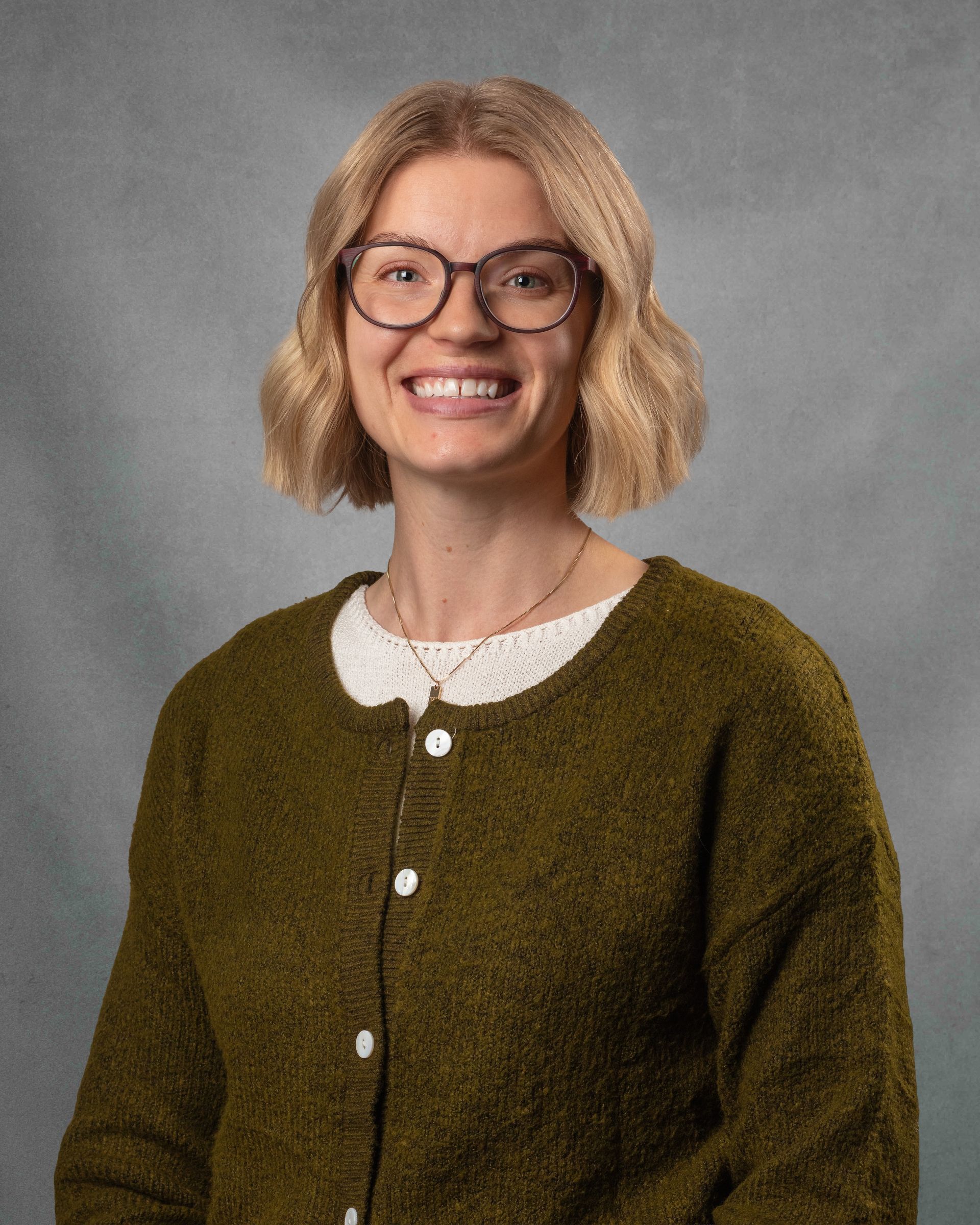 A woman in green sweater is smiling.